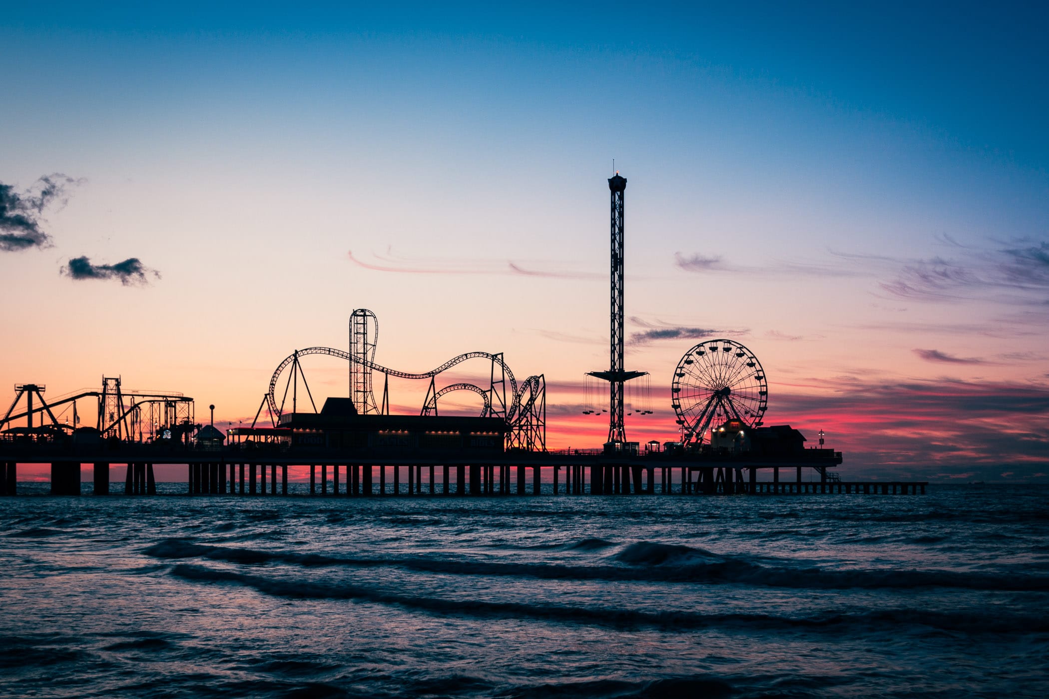 The Galveston Island Historic Pleasure Pier is silhouetted by the sunrise over the Gulf of Mexico.