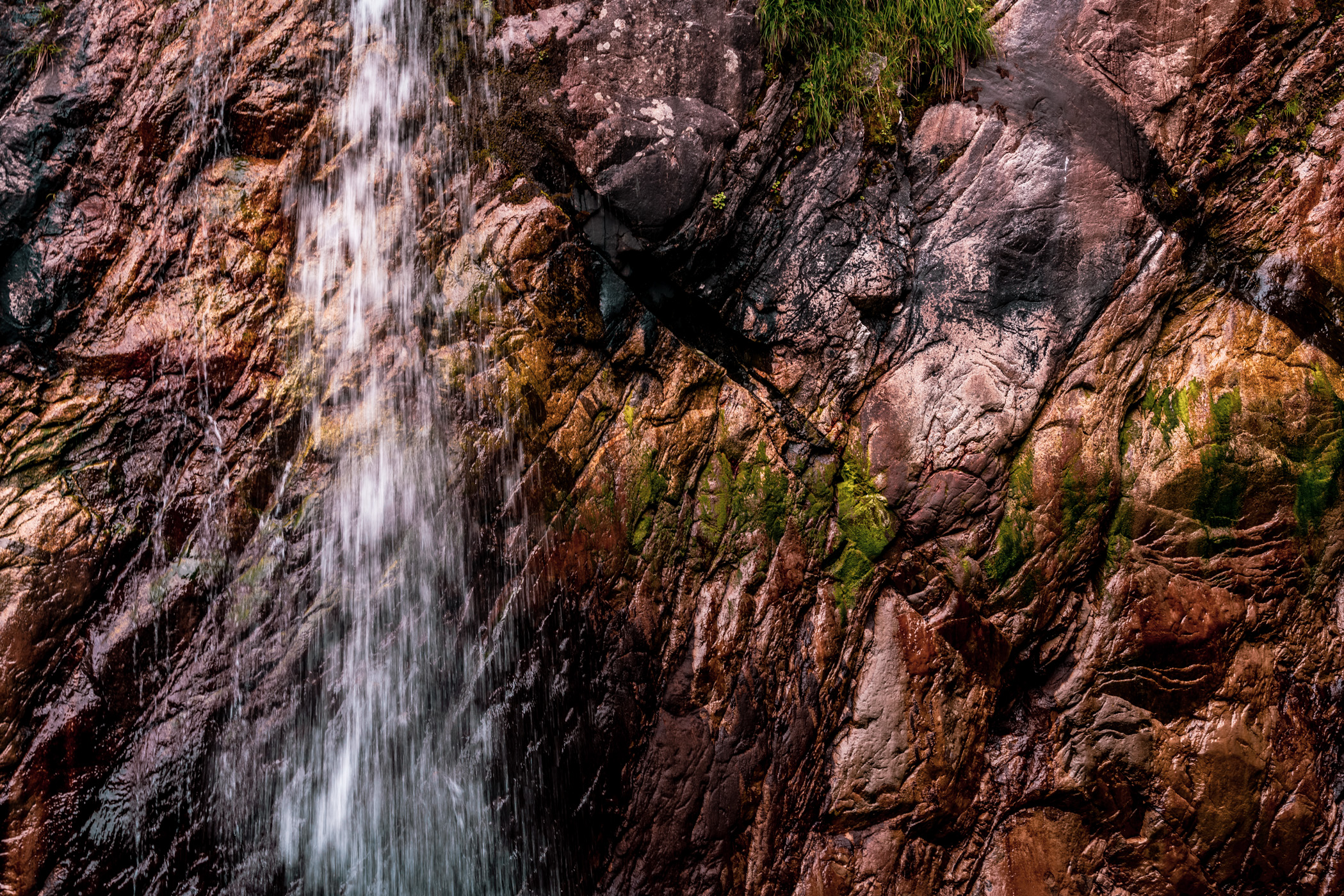 Water cascades down a cliff face along Alaska's Tracy Arm Fjord.