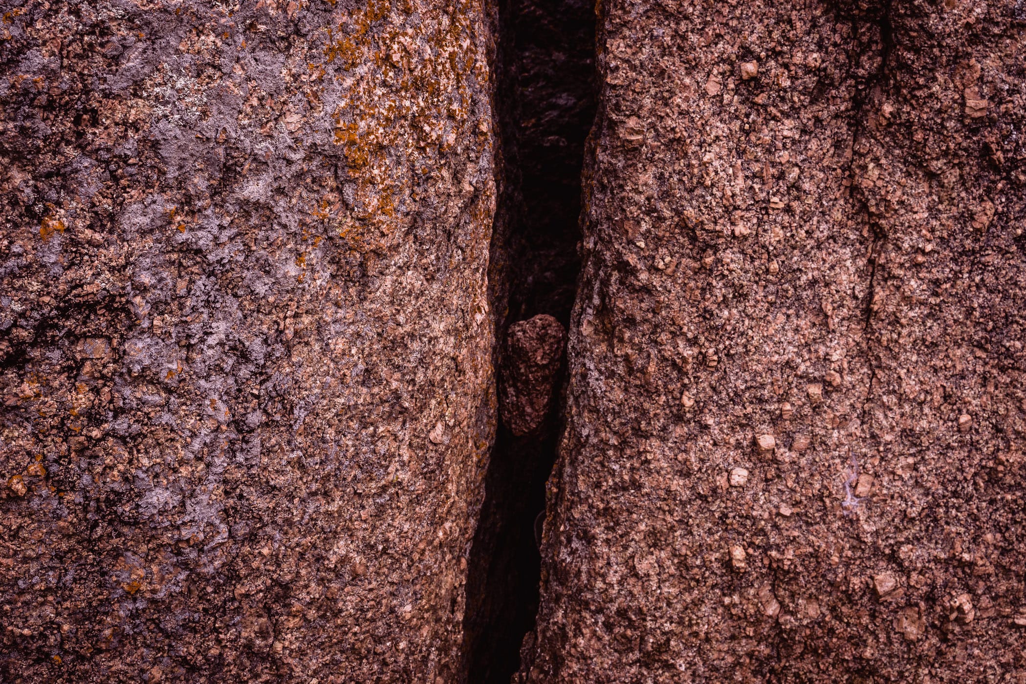 A rock trapped in a chasm between two larger rocks at Enchanted Rock State Natural Area, Texas.
