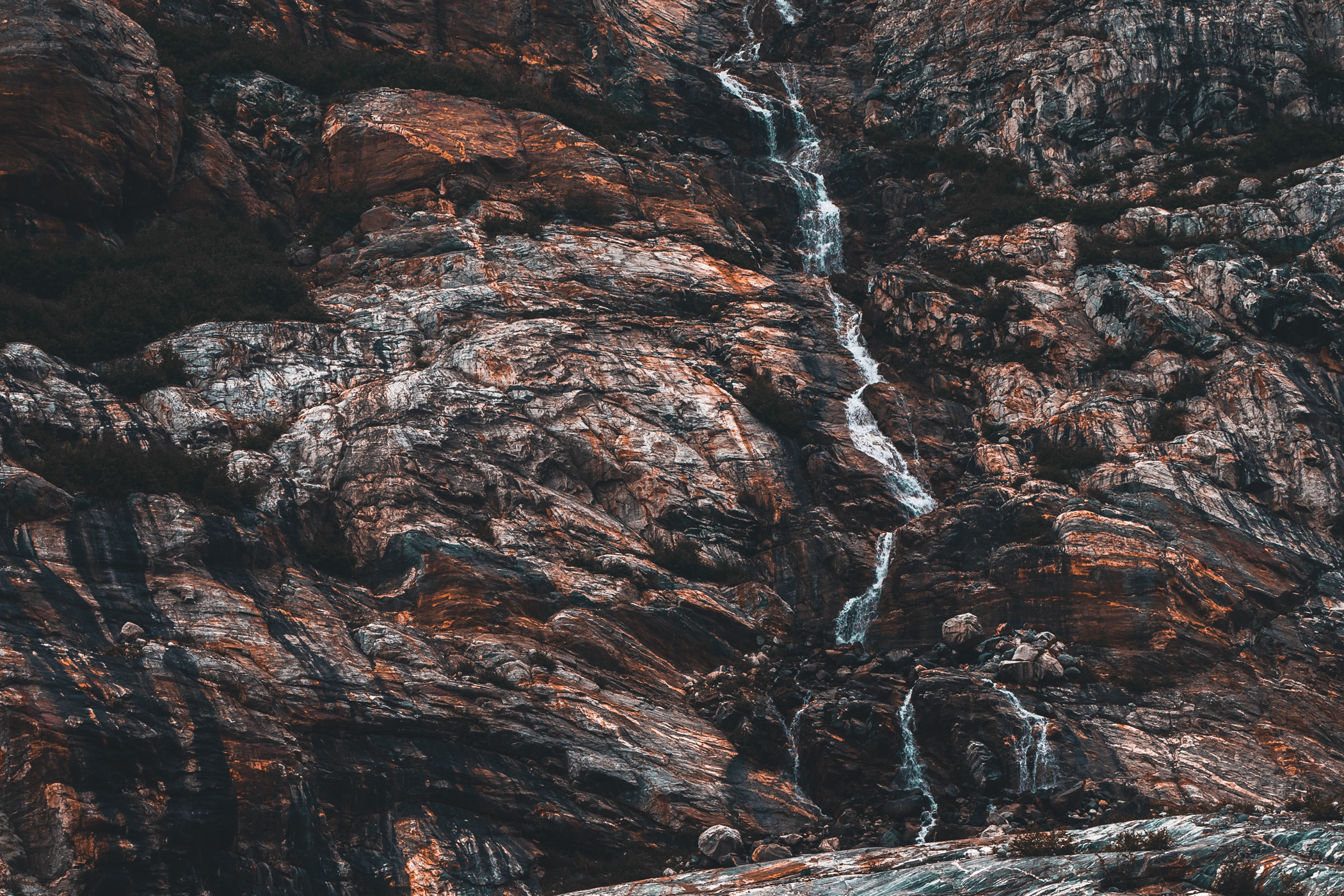 A rivulet of water runs down a rocky cliff in Alaska's Tracy Arm.