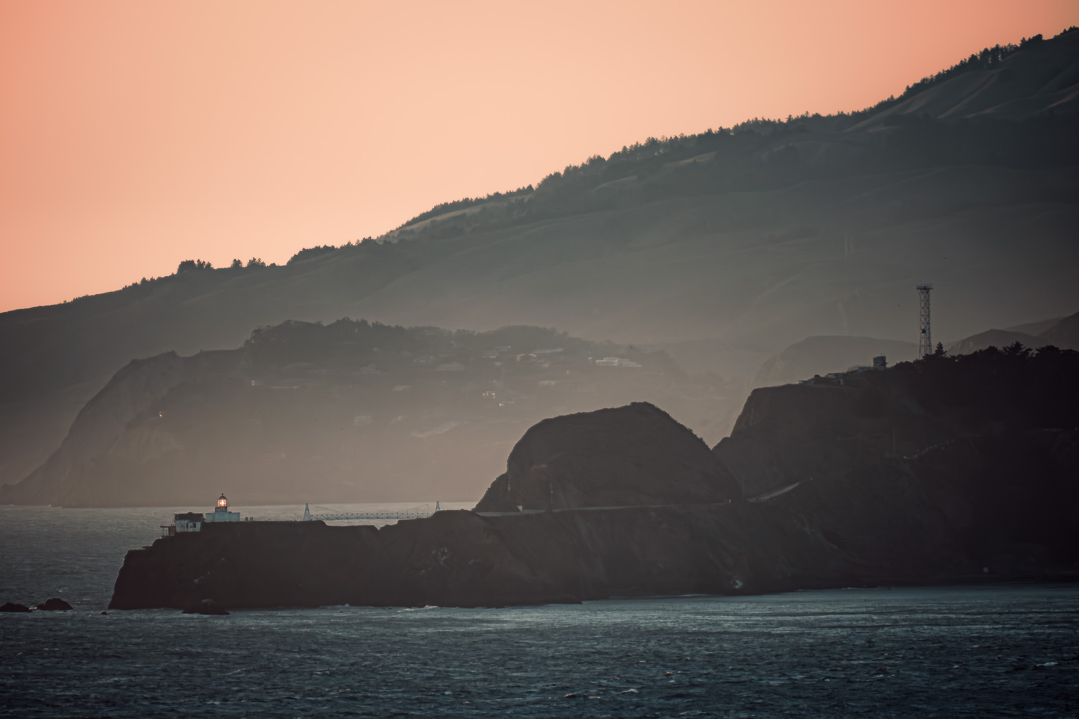 The last light of day on the Point Bonita Lighthouse in the Marin Headlands, California, as seen from Lands End, San Francisco.