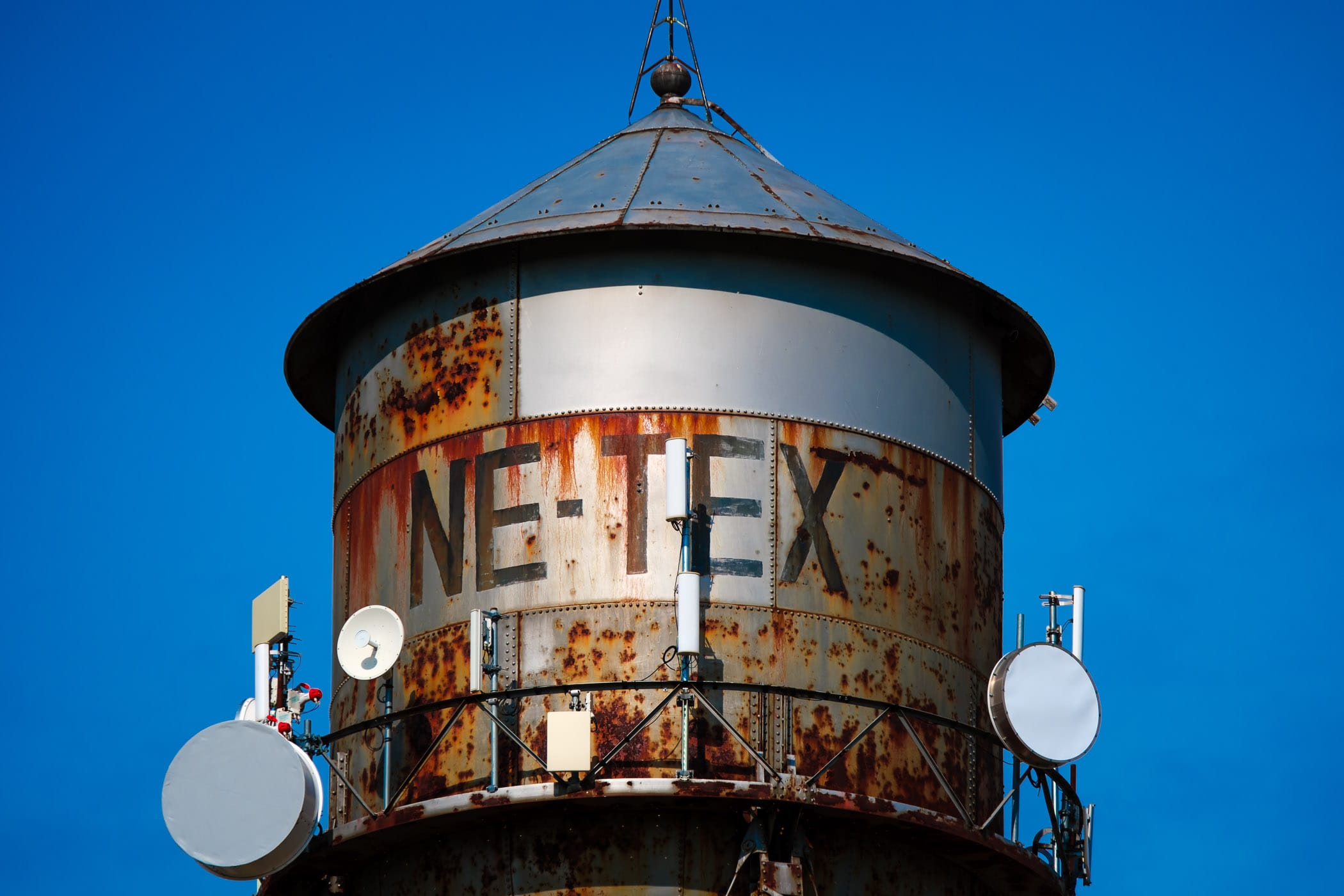 Cellular transmitters on a rusty water tower in Wolfe City, Texas.
