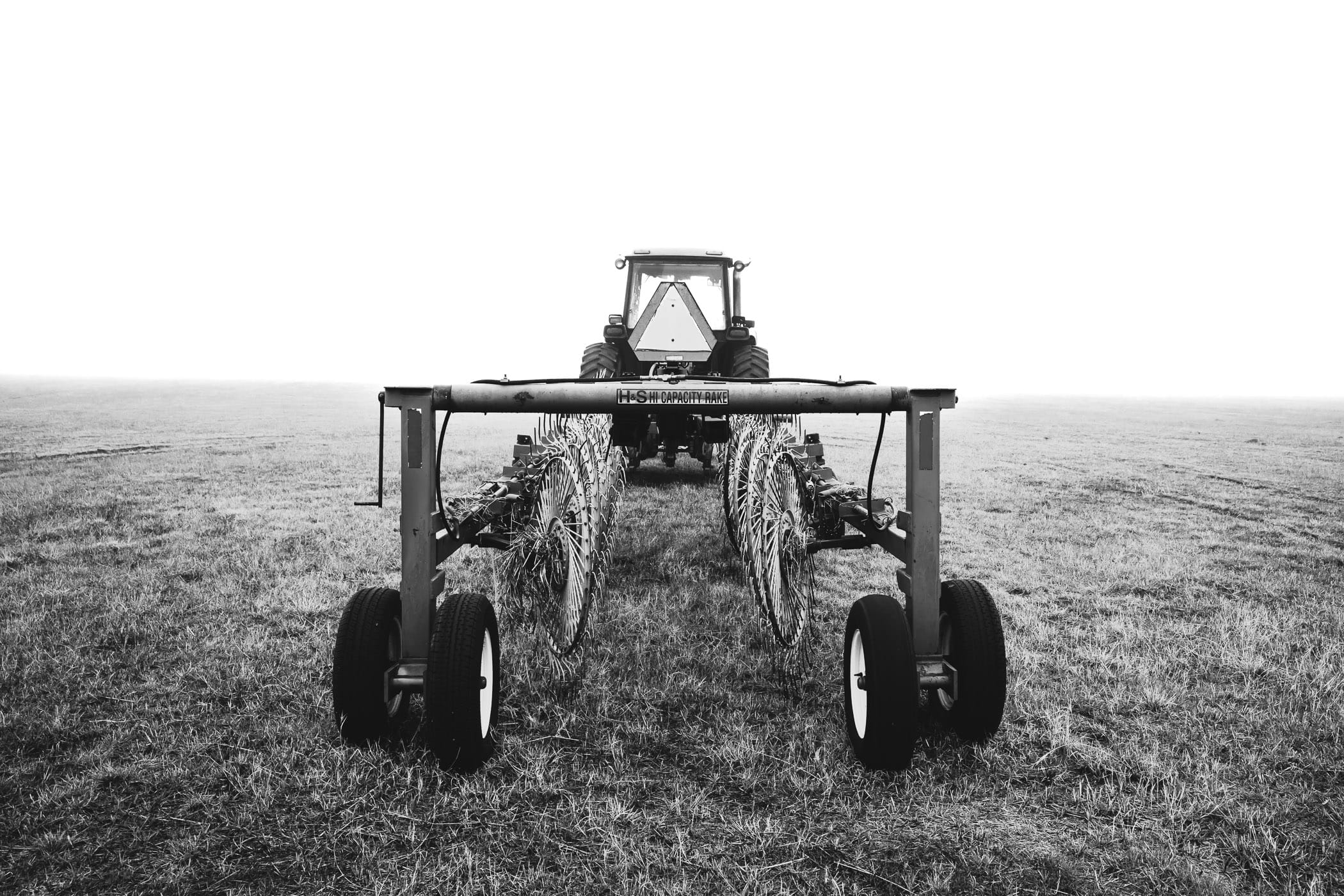 A tractor with a towed hay rake spotted on a foggy day at a North Texas farm.