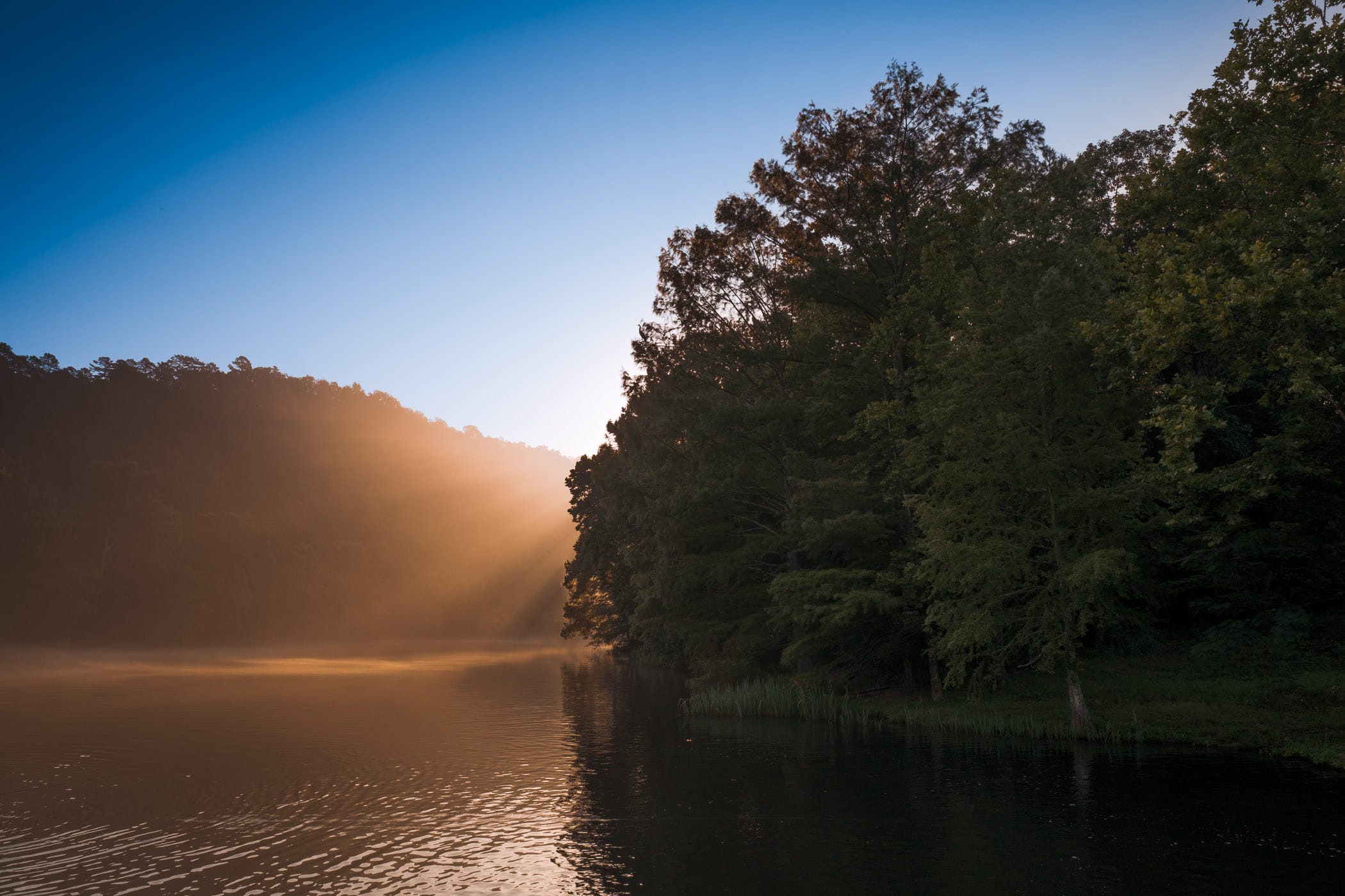 The sunrises on the far side a bend in the Mountain Fork River at Beavers Bend State Park, Oklahoma.