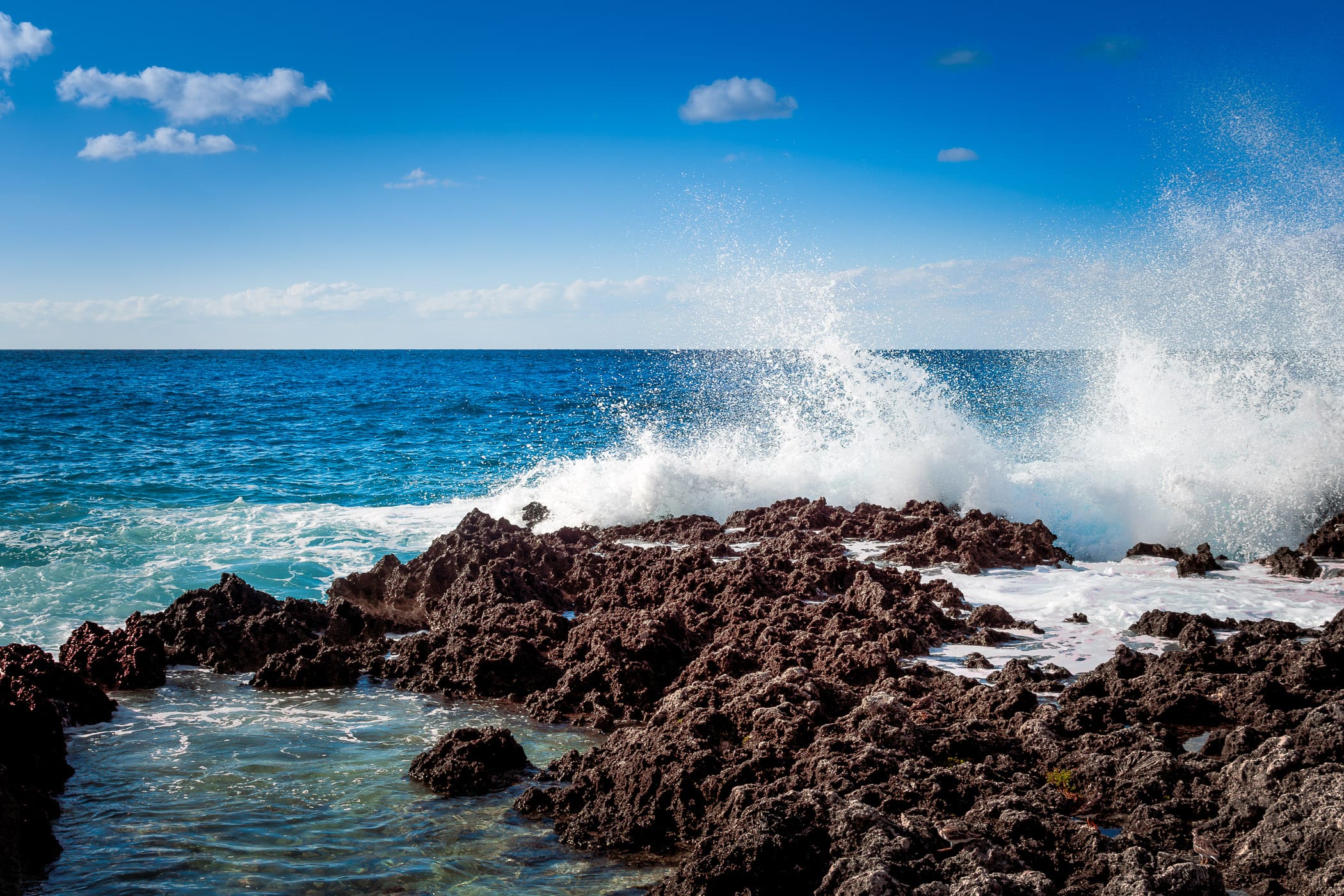 The Caribbean Sea splashes over rocks at Turtle Reef, Grand Cayman.