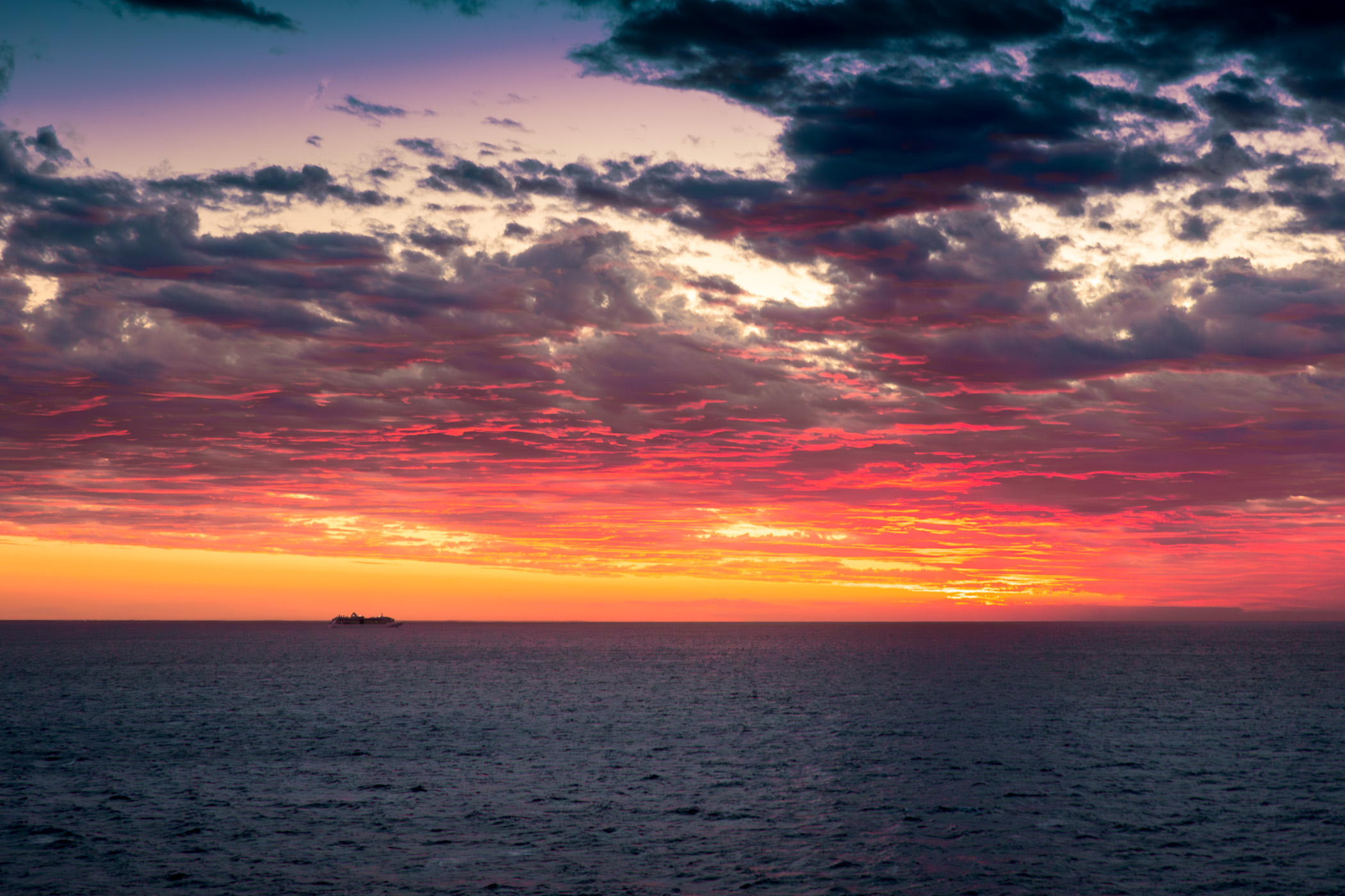 As the sun dips below the horizon, it casts a warm glow over Royal Caribbean's Radiance of the Seas, which is gracefully sailing off the coast of Cozumel, Mexico.