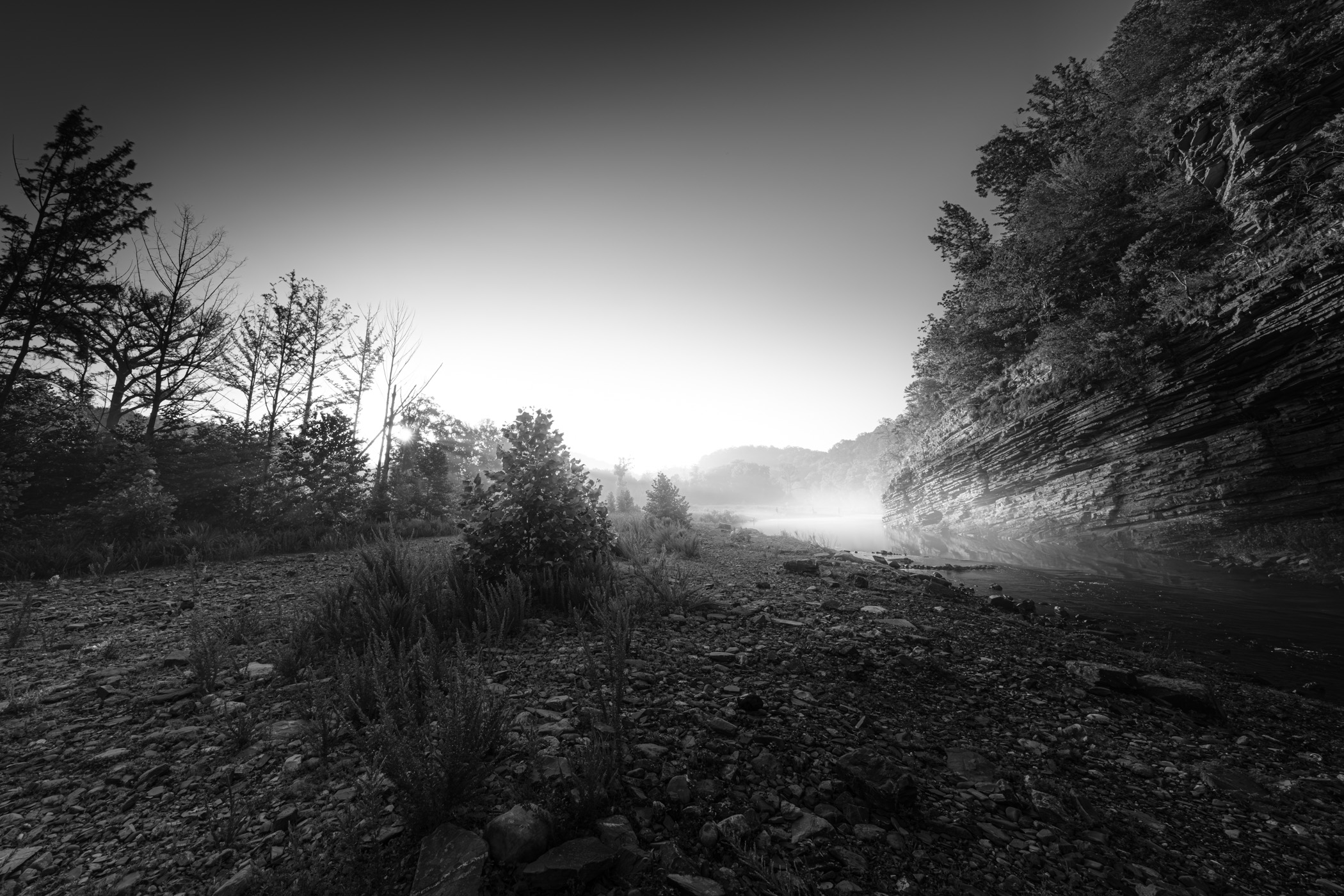 The Mountain Fork River, shrouded in early-morning fog, flows through Beavers Bend State Park in Oklahoma, presenting a serene and mystical landscape.