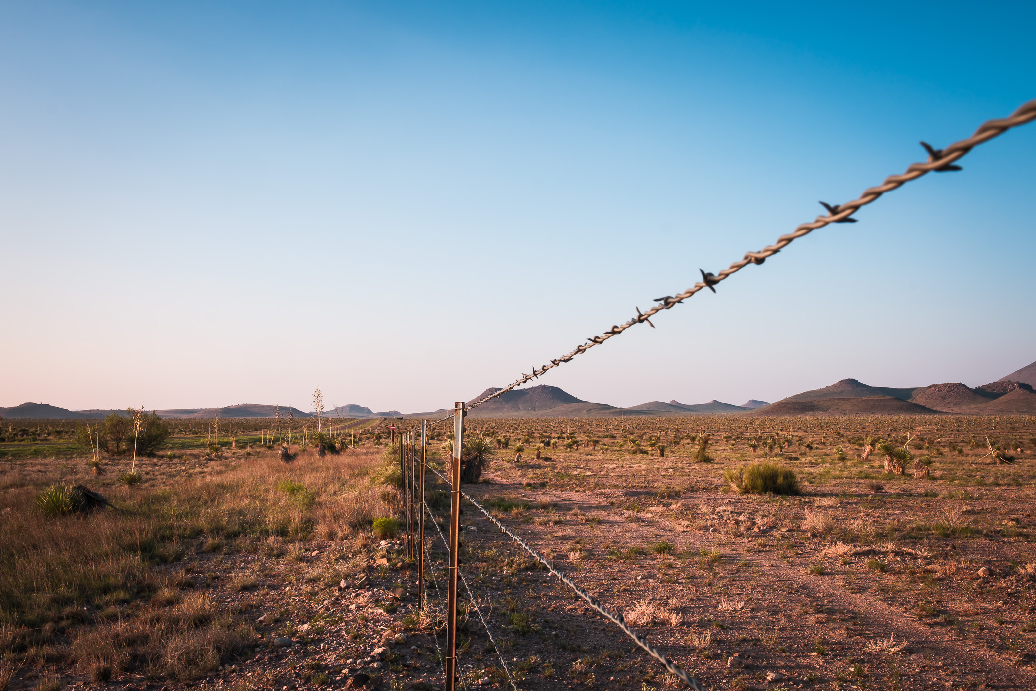 A barbed wire fence stretches towards the Davis Mountains north of Marfa, Texas.